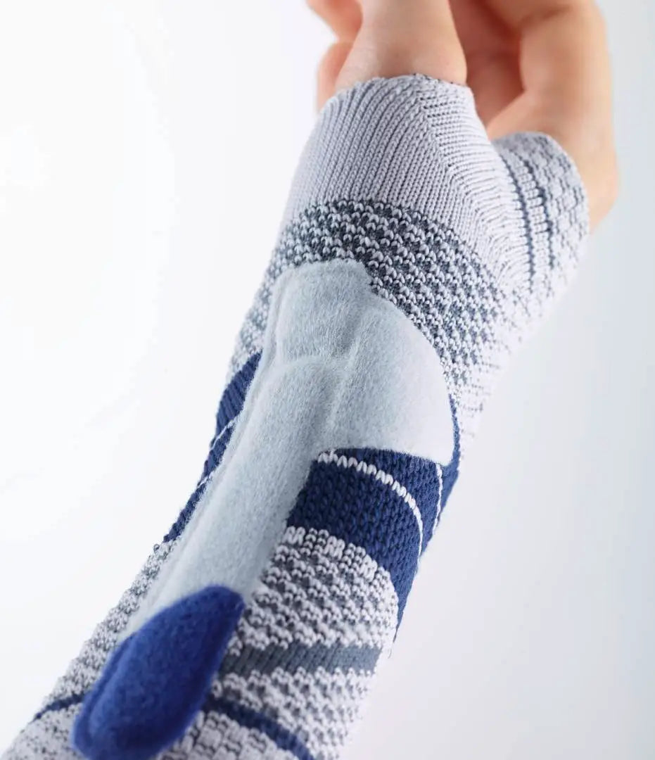 Die Abbildung zeigt die Bauerfeind ManuTrain Bandage, eine stützende Bandage zur Stabilisierung des Handgelenks. Sie besteht aus elastischem, atmungsaktivem Material und ist anatomisch geformt, um sich optimal an das Handgelenk anzupassen. Die Bandage verfügt über integrierte, flexibel einsetzbare Pelotten, die gezielten Druck ausüben und die Muskulatur entlasten.