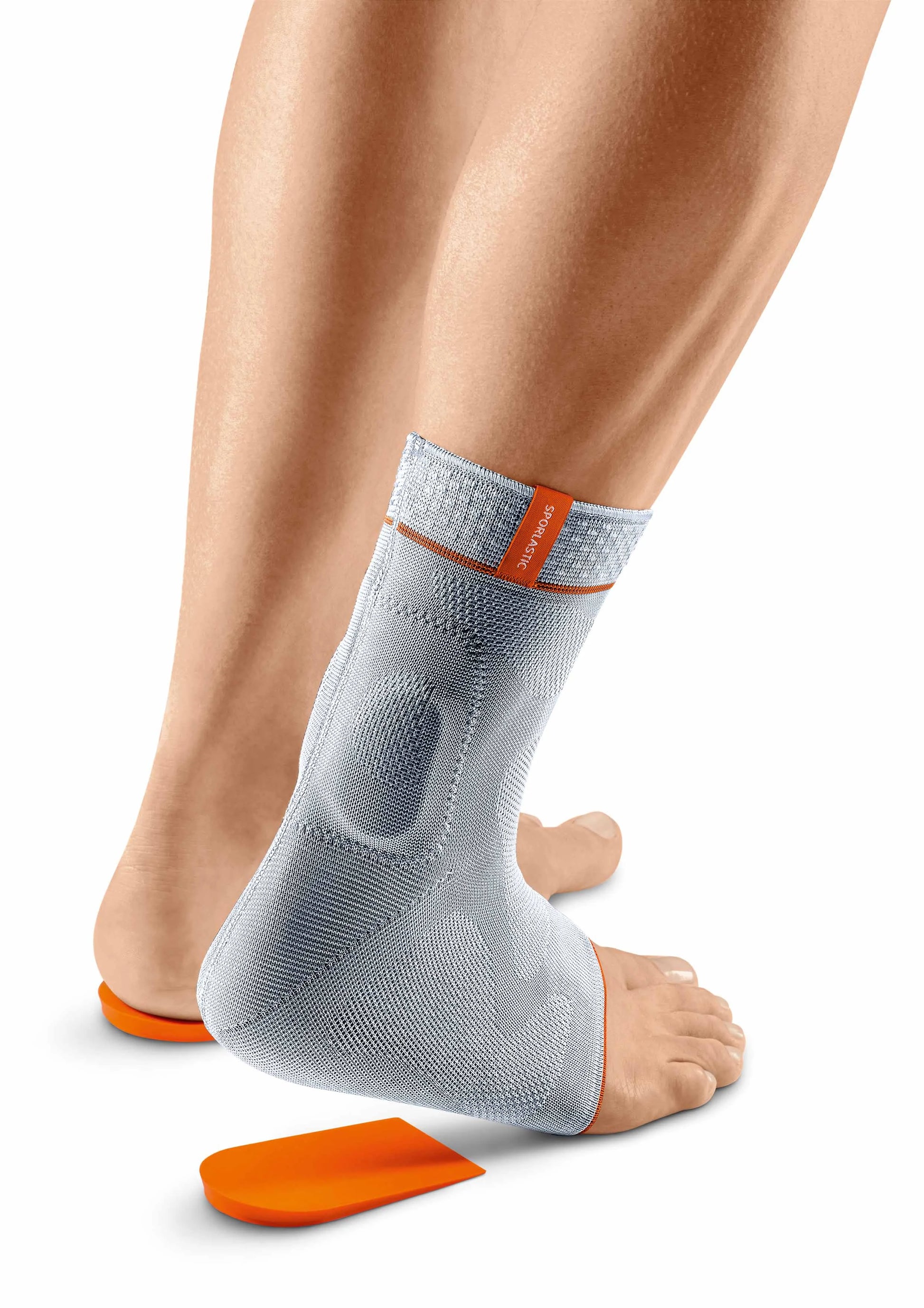 Das Bild zeigt die Sporlastic Achillodyn Achillessehnenbandage in Grau. Die Bandage ist anatomisch geformt und passt sich eng dem Knöchel und der Achillessehne an. Seitlich sind elastische Zonen zu sehen, die für Flexibilität und Bewegungsfreiheit sorgen. Im Bereich der Achillessehne sind zwei Silikonpelotten integriert, die zur Entlastung und gezielten Druckverteilung dienen.